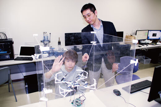 研究室内でゼミ生と研究を進める奥野講師（右）